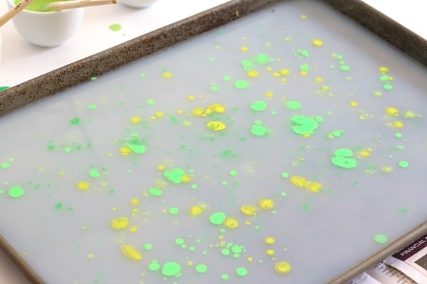 scatter drops of paint over the layer of starch