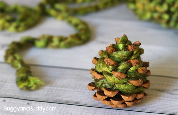 wrap green yarn around pinecone to make apple tree craft for kids